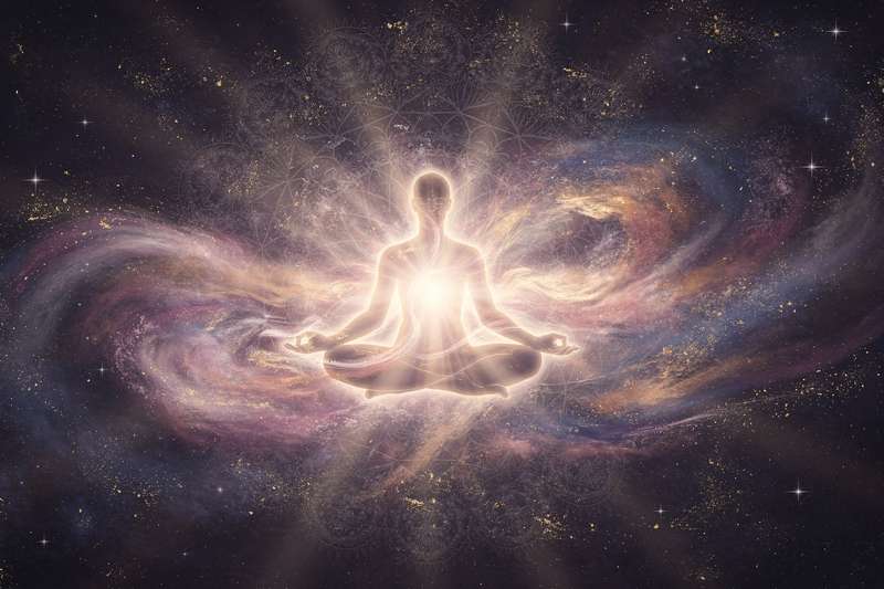 Woman meditating peacefully in nature with sunlight filtering through trees.