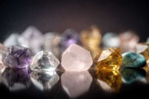 Assorted healing crystals arranged with musical instruments and sheet music on wooden surface.